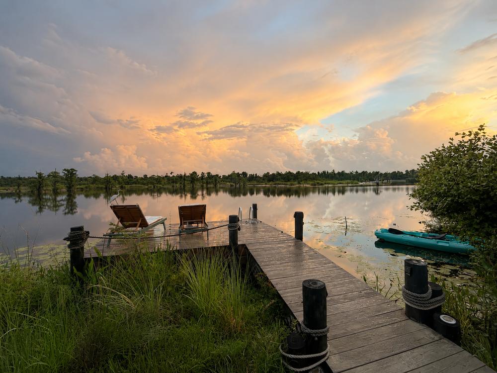 The main dock at dusk with lounge chairs, kayak, and a visiting egret