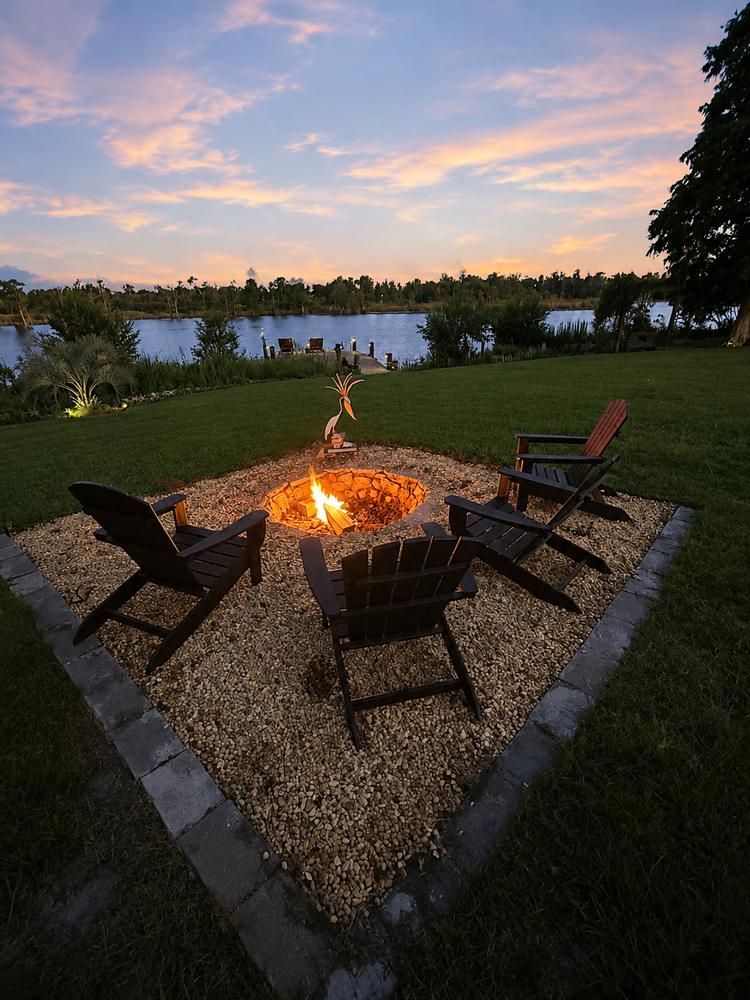 The sunken, built-in fire pit lounge overlooking the lake, lit at dusk