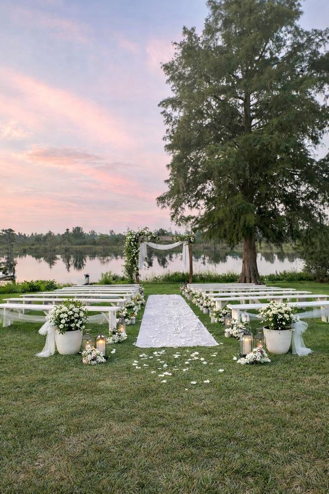 The 2023 waterfront wedding — aisle, benches, and floral arch at the lake