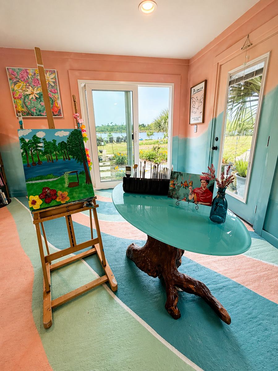 Inside the artist's studio — easel, driftwood table, and the lake through the doors